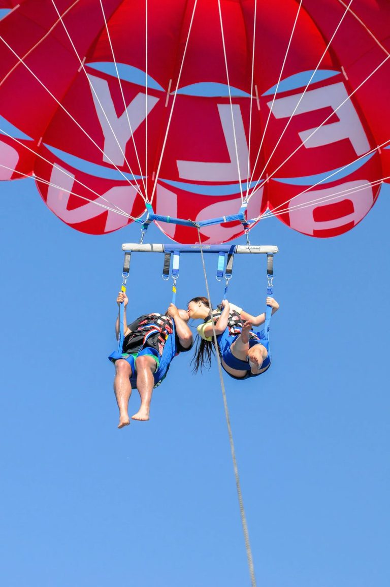 Casal a voar de parasailing sobre o mar em Albufeira