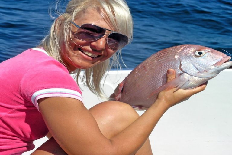 Woman holding a freshly caught fish on a fishing trip